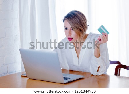 Young girl in white shirt sitting in a table with laptop computer and holding a credit card. Business, education, shopping and other concept