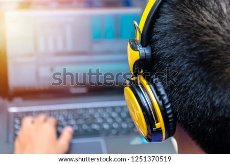 video editing, computer laptops and headphones. with laptop. Professional editor adding special effects or color grading footage. Back view of young man using computer software and wearing headphones.