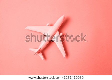 Simply flat lay design miniature toy model plane colored in trendy color of year 2019 Living Coral background. Bright Macro color 16-1546. Travel by plane vacation adventure trip journey tour concept