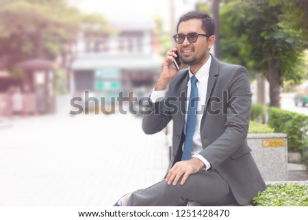 Asian businessman talking on smartphone while sitting outdoor