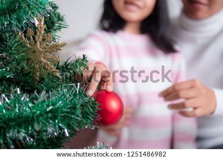 Asian little girl with mother decorating christmas tree for party with happiness, Select focus shallow depth of field