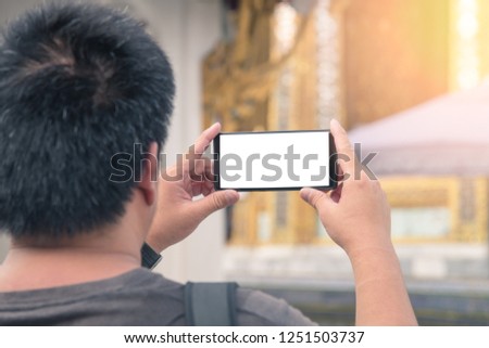 Traveling Asian male tourist backpackers taking photo, Temple of the Emerald Buddha and the home of the Thai King. Wat Phra Kaeo is one of Bangkok's most famous tourist sites and it was built in 1782 