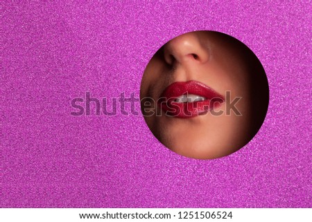 Beauty salon advertising banner with copy space. View of bright lips with glitter through hole in violet paper background. Make up artist, beauty concept. Ready to new year party. Cosmetics sale