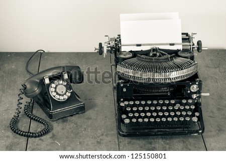Vintage phone, old typewriter on table desaturated photo