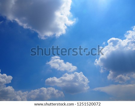 Clear blue sky with fluffy clouds and sun ray for background.