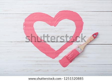 pink painted heart with paintbrush on white wooden background