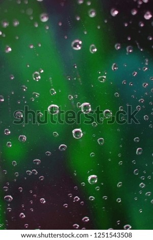 Complex, incomprehensible, original and interesting texture, pattern and background of transparent glass with drops of water from the rain on the surface of the glass against the background of nature.