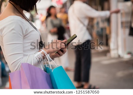 Happy girl with phone and colorful shopping bags. Quick and easy to order online, searching for discounts and sales
