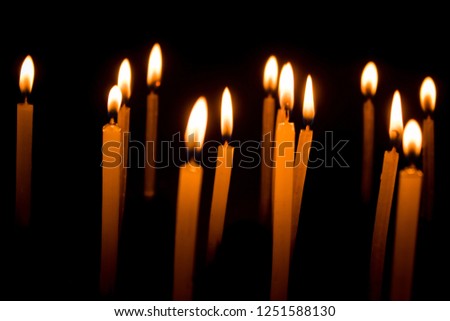 Many candles burning at night on the black background.  Group of burning candles in dark with shallow depth of field. Close-up. 