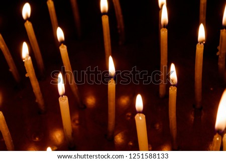 Many christmas candles burning at night in temple. Candle flame set isolated in black background. Top View.