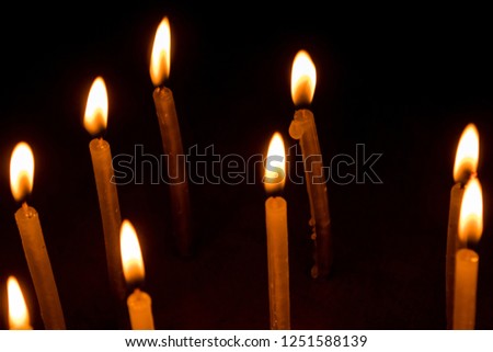 Group of burning candles in dark with shallow depth of field. Close-up. Free space.