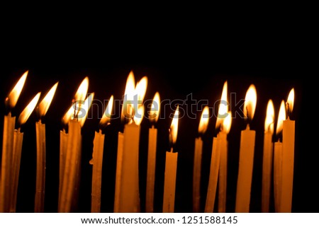 Many Christmas candles burning at night on the black background. Group of burning candles in temple with shallow depth of field. Close-up. Free space on top of image.