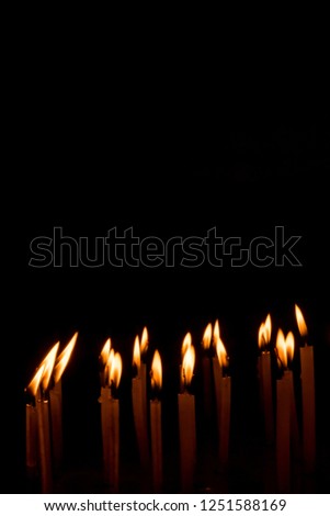 Candle spreading light isolated on black background. Horizontal. Free space.