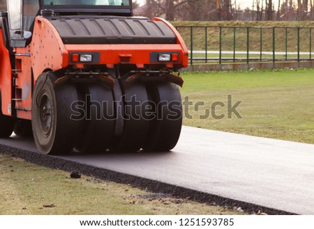 Laying asphalt with the help of heavy special equipment. The construction of the road. Modern technologies laying highway with a solid surface. People work at a construction site. Rolling asphalt.