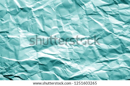 Crumpled sheet of paper in cyan color. Abstract background and texture for design.