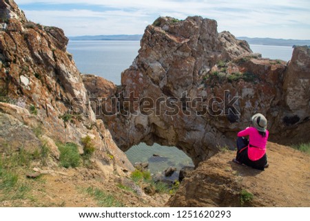 Woman taking picture of natural arch on lake Baikal