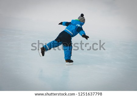 little boy skating on ice in winter