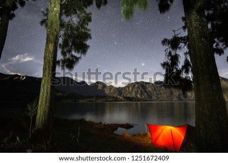 Tents at the starry night with lake reflection
