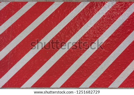 Sticker texture with red and white stripes diagonally on a concrete surface.