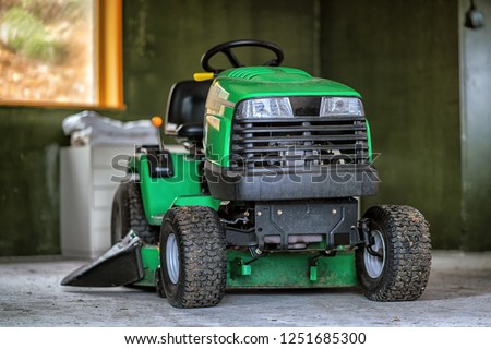 Picture of green lawn mower in the garage.