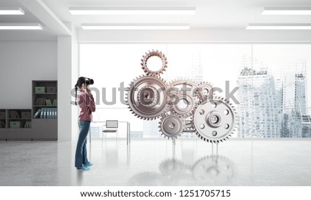 Young woman wearing virtual mask and working with metal gear mechanism. Mixed media