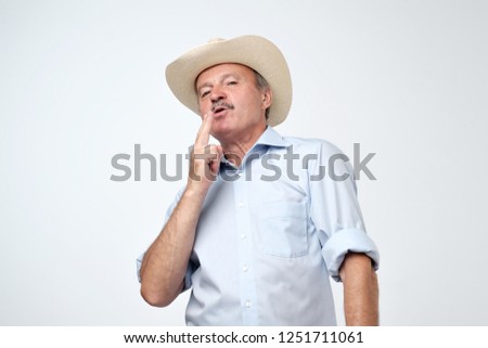 Senior man in cowboy hat pretending that he is smoking a cigar