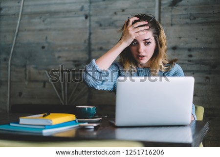 Worried stressed woman forgot about important think during remote work at laptop computer in cafe interior.Hipster girl done stupid mistake during freelance deadline on netbook sitting at table Royalty-Free Stock Photo #1251716206