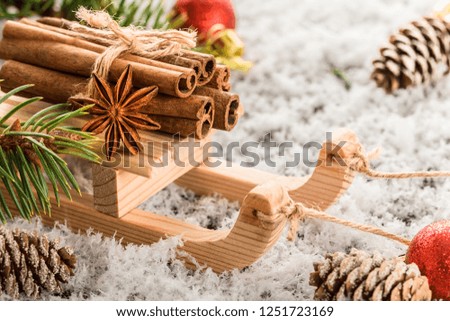     Christmas card with wooden sled with heap of cinnamon with falling snow. Christmas greeting card. winter holiday composition. New Year and Christmas celebration.  