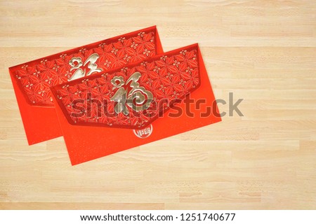 Two red envelope packet Chinese New Year. Hong-bao or Ang-bao with character gold color "HOK" or "FU". It's mean Good luck, Happy. Inside have money to give to someone you love. Copy space.