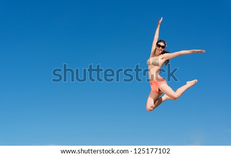 beautiful young woman jumping on a background of blue sky, having a fun time