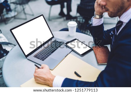 Cropped image of businessman reading financial news on website for planning organisation schedule using 4g internet connection on laptop computer with advertising area sharing files with tablet