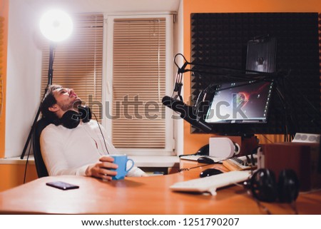 Portrait of handsome young latin man sitting in front of a microphone with laptop at radio station.