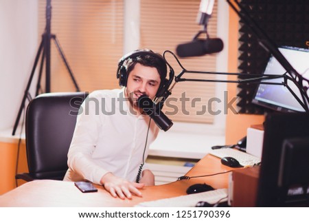 Portrait of radio host using sound mixer on table in studio.
