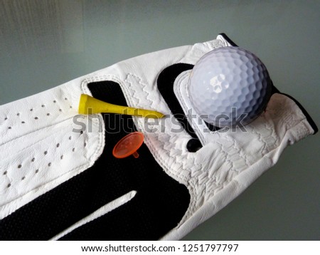 soft white leather golf glove close-up with tee and marker peg. golf concept, golf equipment and golf apparel illustration condensed in one shot or hole in one.
