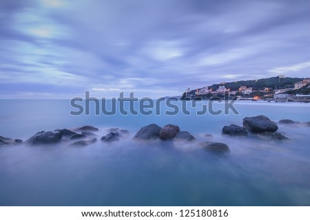 Dark Rocks in a blue ocean on twilight. Castiglioncello, Tuscany, Italy. Long exposure photography