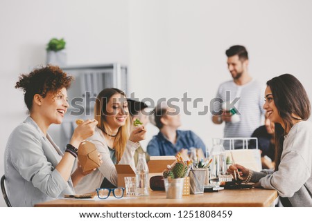 Three smiling friends taking lunch break at the office Royalty-Free Stock Photo #1251808459