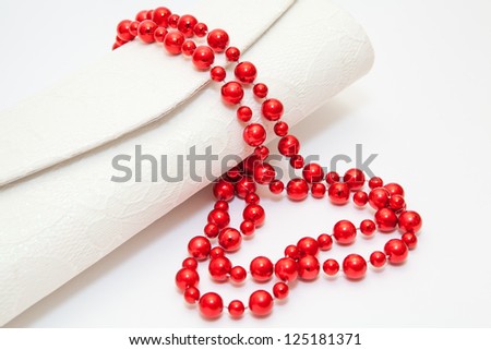 Red pearl necklace with small purse on white background