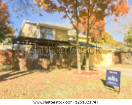 Abstract blurred traditional single-family house with for sale yard sign in fall season near Dallas, Texas, USA