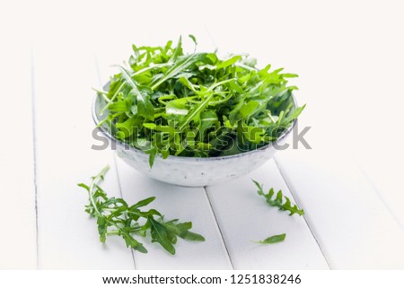 Bowl with fresh green salad arugula rucola on a wooden Black or White background