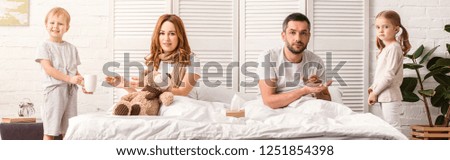 panoramic view of children supporting sick mother and father in bedroom