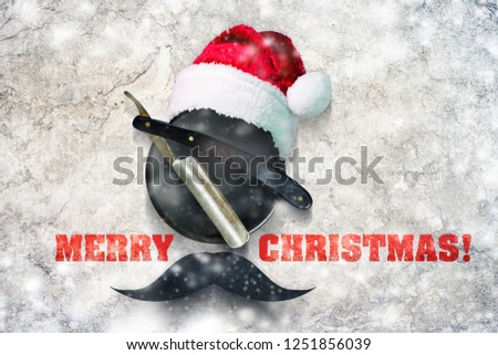 Razor on a plate for foam with a Santa Claus hat on a gray background. Inscription Merry Christmas. Greeting card Happy New Year and Merry Christmas for a hairdresser and barber shop. Snow effect