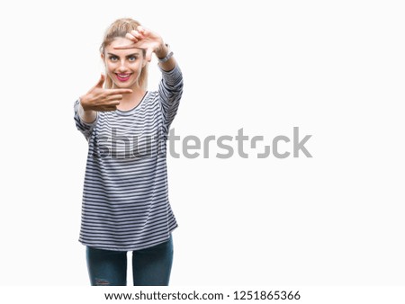 Young beautiful blonde woman wearing stripes sweater over isolated background smiling making frame with hands and fingers with happy face. Creativity and photography concept.