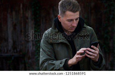 
portrait of a young trendy stylish casual guy with a phone in his hands. Winning emotions, victory