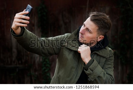 
Portrait of a happy casual man taking a selfie and wearing warm clothes in winter.