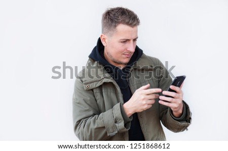
portrait of a young trendy stylish casual guy with a phone in his hands. Winning emotions, victory
