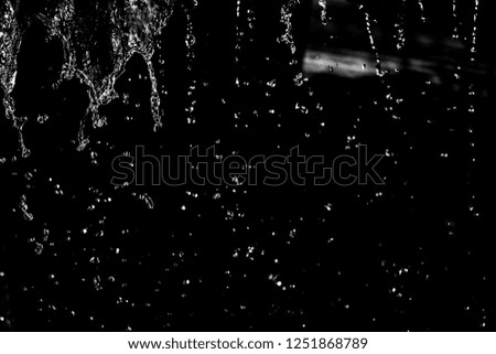 Water splash in dark with a drops of water flying, defocused bokeh.