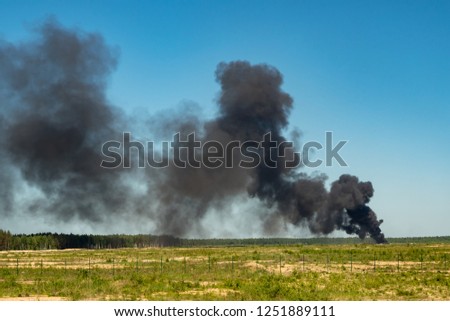 black smoke in a green field Royalty-Free Stock Photo #1251889111