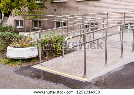 Concret ramp way with stainless steel handrail with disabled sign for support wheelchair disabled people. Health care concept.metallic stair railing outside building
