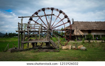 Ancient baler or water turbine in Ban Na Pa Nat, Tai Dam Ethnic Cultural Village, Loei Province, Thailand. Royalty-Free Stock Photo #1251926032
