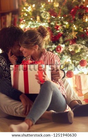 Young couple opening a present on a Christmas at home

